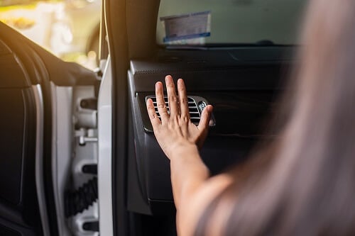 Car Aircon Services in Columbia, MD | Columbia Auto Care & Car Wash. Close-up image of a woman’s hand checking the flow of cold air from her car’s air conditioner.