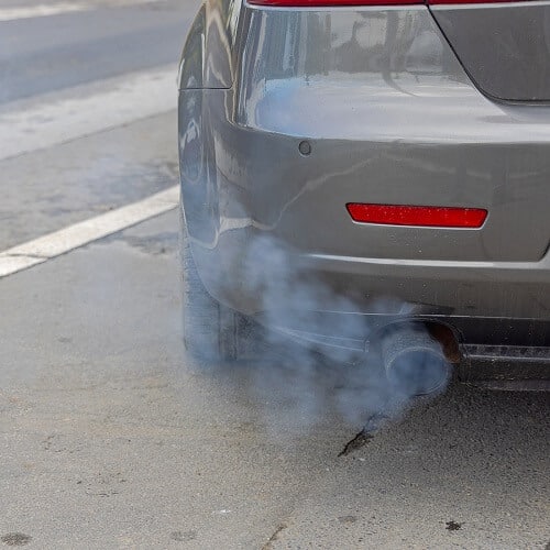 Emissions Repair in Columbia, MD | Columbia Auto Care & Car Wash. Image of a back of a car emitting black exhaust fumes and needing emissions repair.