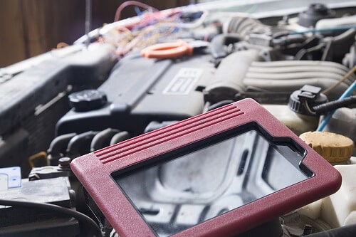 Engine Diagnostics in Columbia, MD | Columbia Auto Care & Car Wash. Image of a scanner for car diagnostics with car engine in the background.