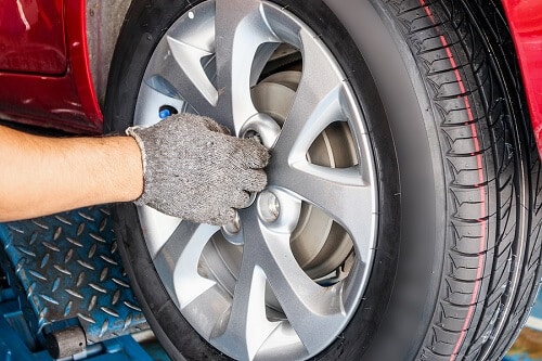 Tire Services in Columbia, MD | Columbia Auto Care & Car Wash. Image of a car mechanic working at an auto repair shop installing or changing tires.