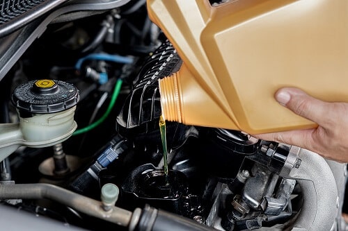 Oil Changes in Columbia, MD by Columbia Columbia Auto Care & Car Wash. Closeup image of a man’s hand pouring fresh oil to a car engine during car maintenance