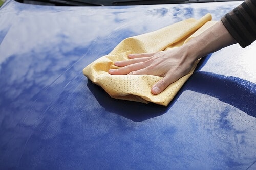 Choosing a Premium Car Wash | Columbia Auto Care & Car Wash. Closeup image of hand drying a blue car.