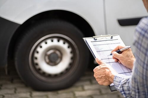 Will Your Tires Pass Maryland State Inspection? | Columbia Auto Care & Car Wash in Columbia, MD. Image of a vehicle safety inspector doing a car tire check.