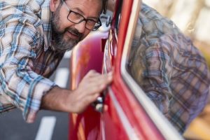 5 Reasons to Head to the Car Wash (Without Breaking the Bank) | Columbia Auto Care & Car Wash in Columbia, MD. Image of a happy man admiring his clean and polished red car.
